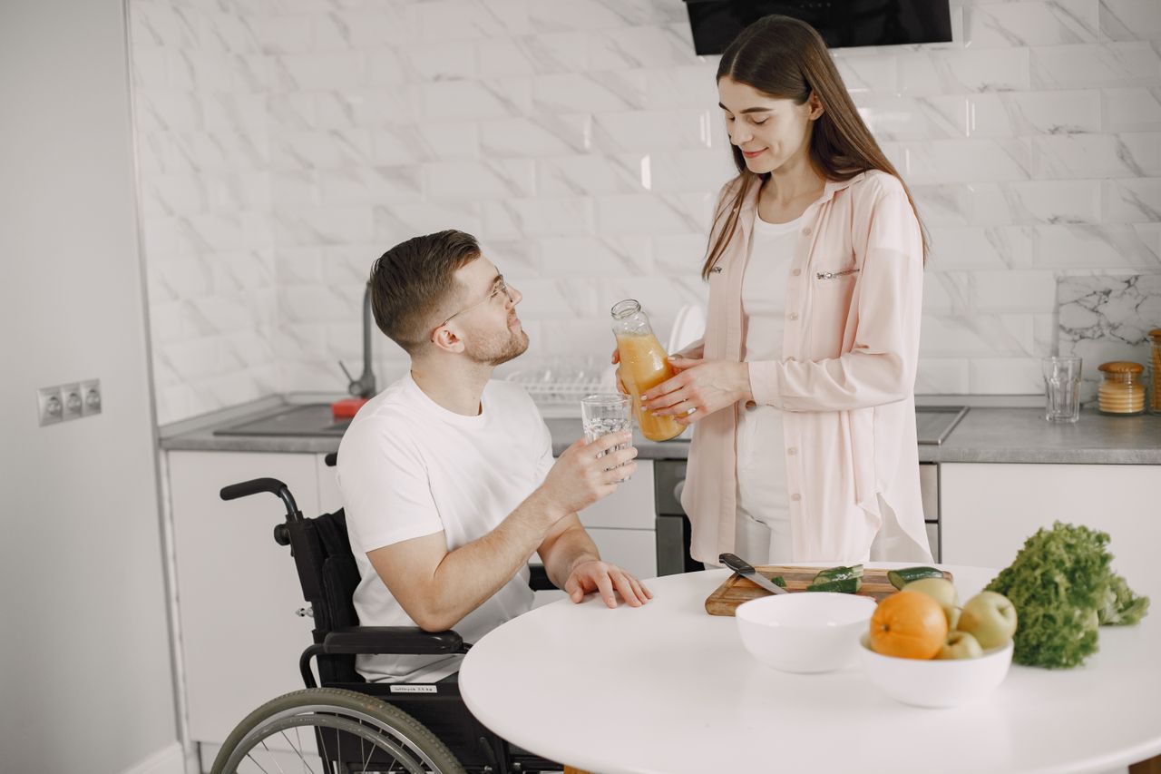 Couple enjoying time together in a kitchen, sharing a drink. Love and care in action.