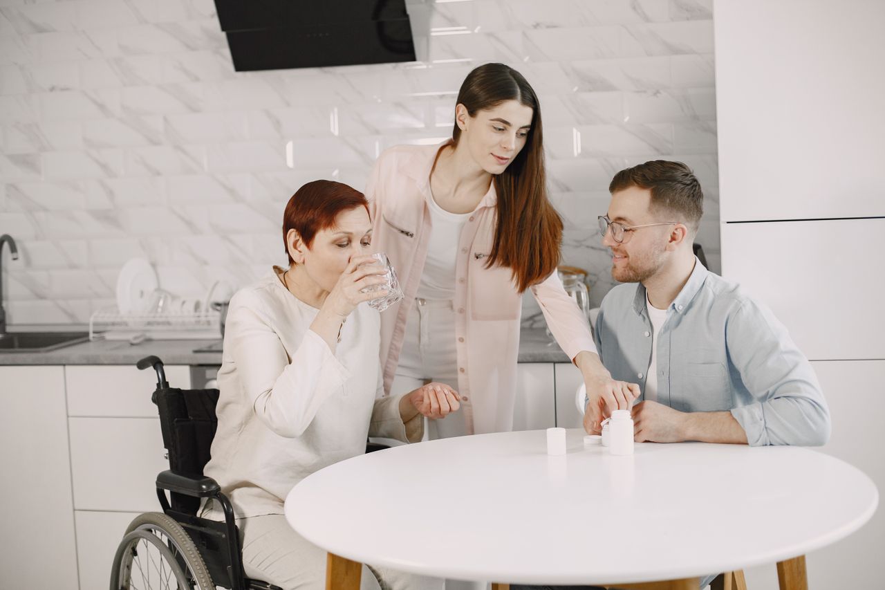 About Family members providing care and companionship to an elderly woman in a modern kitchen.